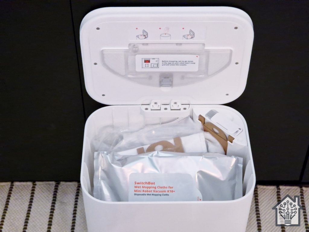SwitchBot K10+ robot vacuum's docking station, showing the mopping module, wet wipe pack, and dust bag